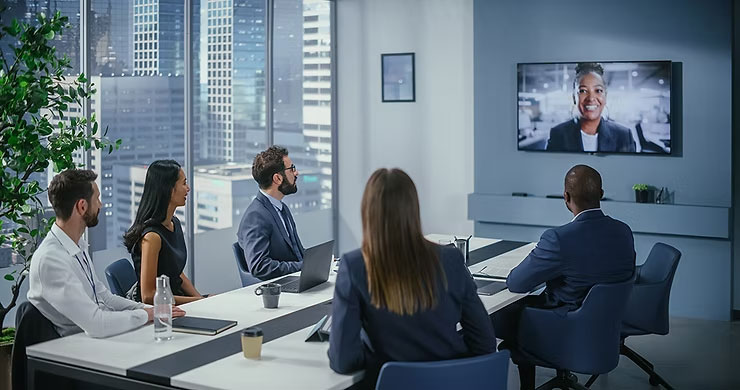 Attendees in a conference room focused on a video being shown