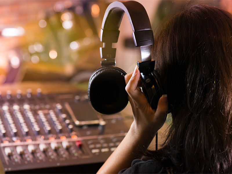 Person wearing headphones at an audio mixing console.