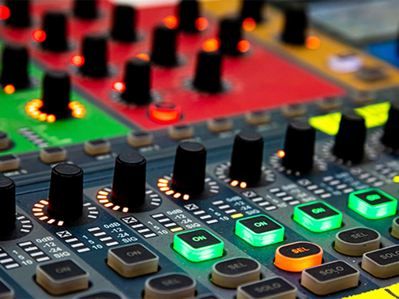 Close-up of audio mixing board with control knobs and buttons.